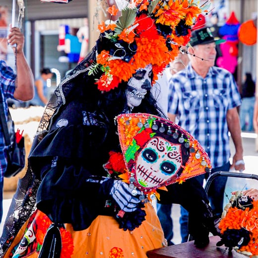 Two catrinas in black lace with full calavera face paint greeting the crowd.