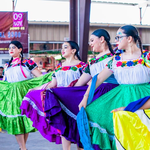 Folklórico dancers spinning in bright layered skirts under the pavilion.
